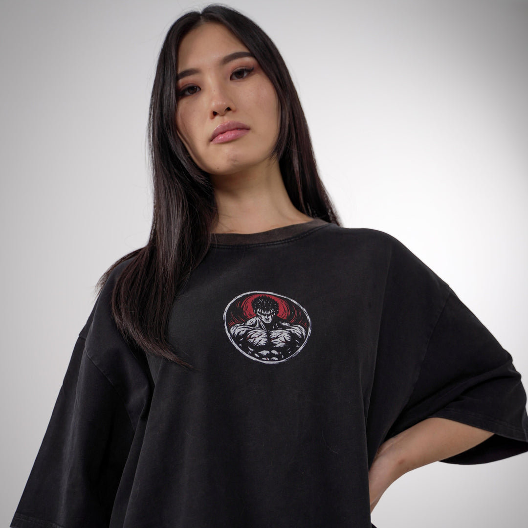 Model showcasing the Guts Berserk Oversized Tee featuring a small front chest print and a large detailed back design of Guts in rage mode, with red and black accents on a heavyweight black cotton shirt.