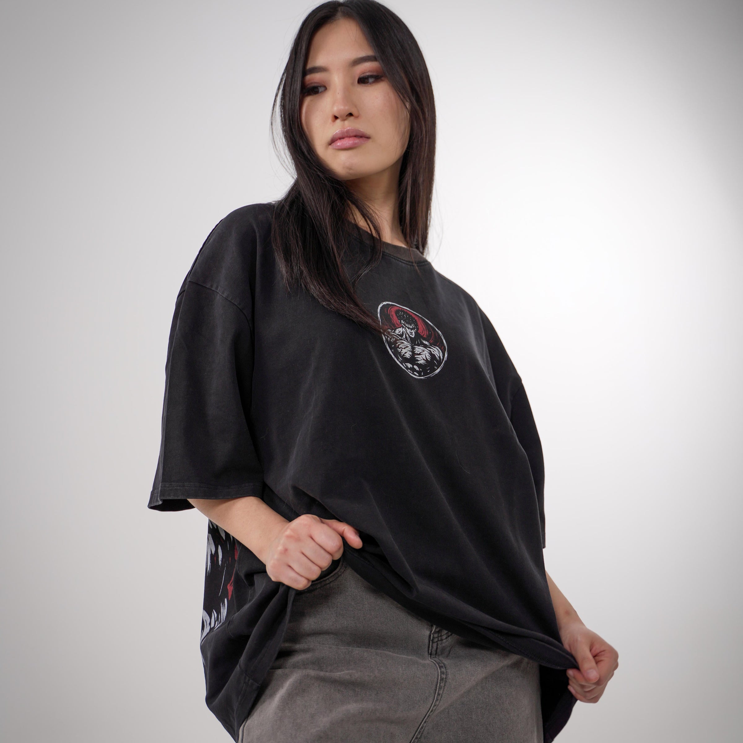 Model showcasing the Guts Berserk Oversized Tee featuring a small front chest print and a large detailed back design of Guts in rage mode, with red and black accents on a heavyweight black cotton shirt.